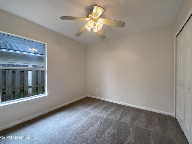 unfurnished room featuring dark carpet and ceiling fan