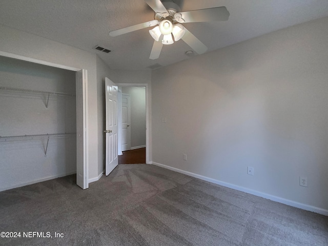 unfurnished bedroom with ceiling fan, a closet, and dark colored carpet