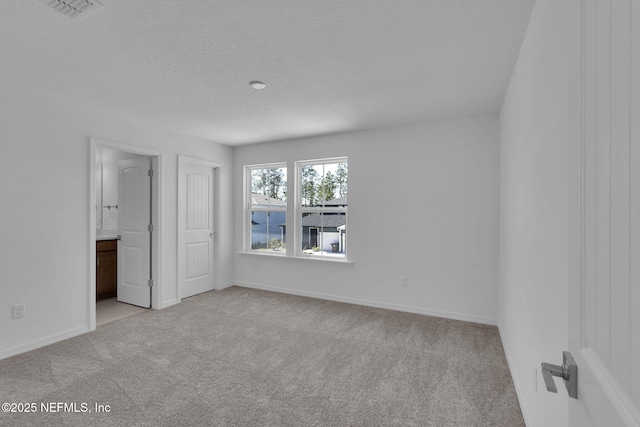 carpeted empty room featuring a textured ceiling, visible vents, and baseboards