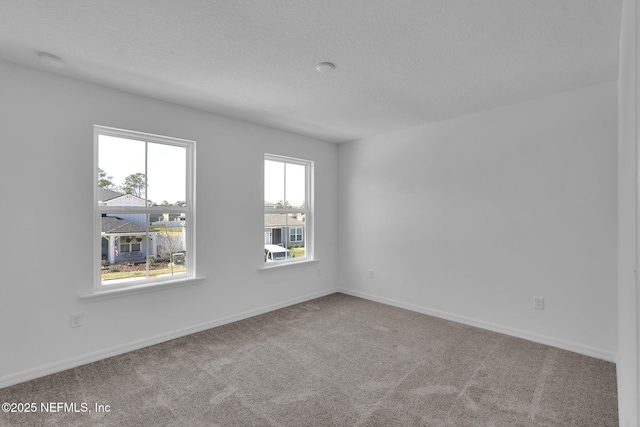 unfurnished room featuring carpet flooring, a textured ceiling, and baseboards