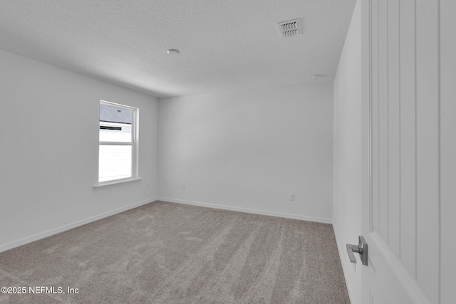 carpeted empty room featuring baseboards, visible vents, and a textured ceiling