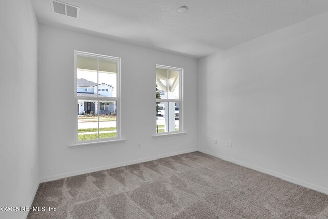 unfurnished room featuring carpet, a textured ceiling, visible vents, and baseboards