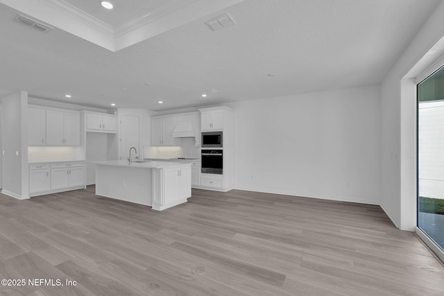 kitchen featuring stainless steel microwave, visible vents, wall oven, open floor plan, and a sink