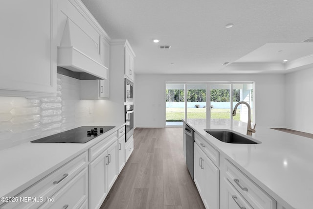 kitchen featuring custom range hood, a sink, stainless steel appliances, light countertops, and backsplash