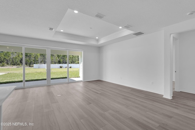 unfurnished room with recessed lighting, visible vents, a tray ceiling, and wood finished floors