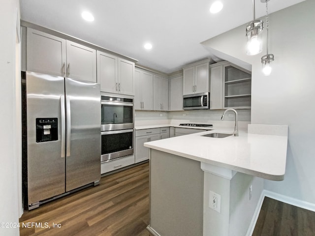 kitchen featuring kitchen peninsula, appliances with stainless steel finishes, gray cabinetry, sink, and decorative light fixtures