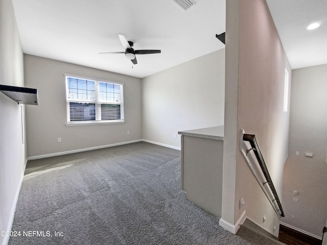 unfurnished living room featuring dark colored carpet and ceiling fan