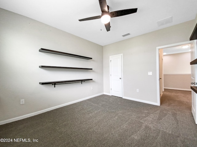 unfurnished bedroom with ceiling fan and dark carpet