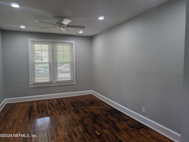 empty room with dark wood-style flooring, a ceiling fan, and baseboards