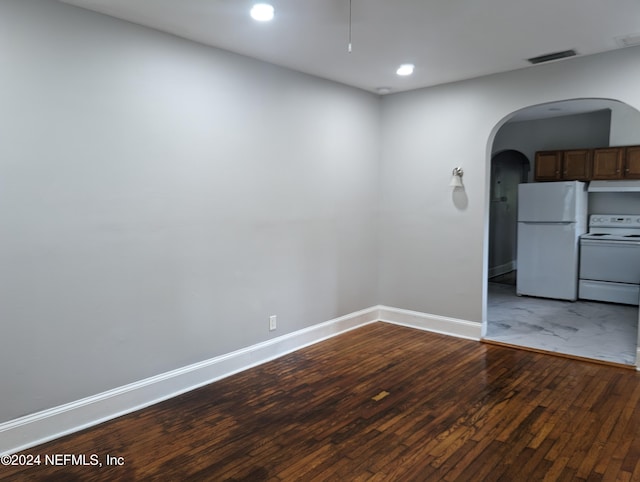 unfurnished room with baseboards, visible vents, arched walkways, and hardwood / wood-style floors