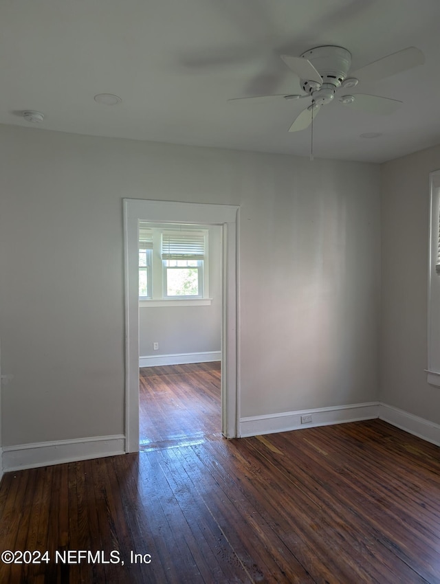 spare room featuring wood-type flooring, a ceiling fan, and baseboards