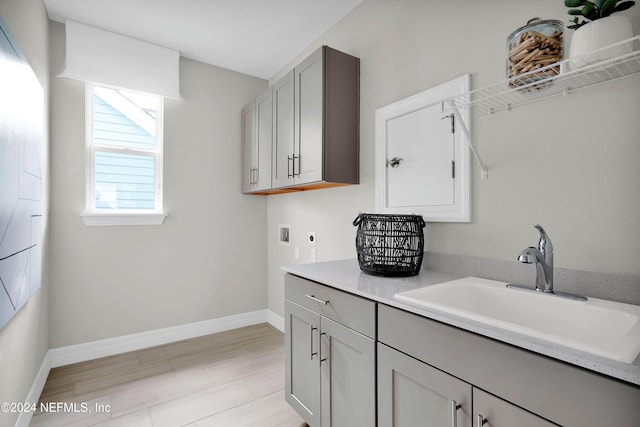 laundry room with cabinets, sink, light hardwood / wood-style flooring, washer hookup, and hookup for an electric dryer