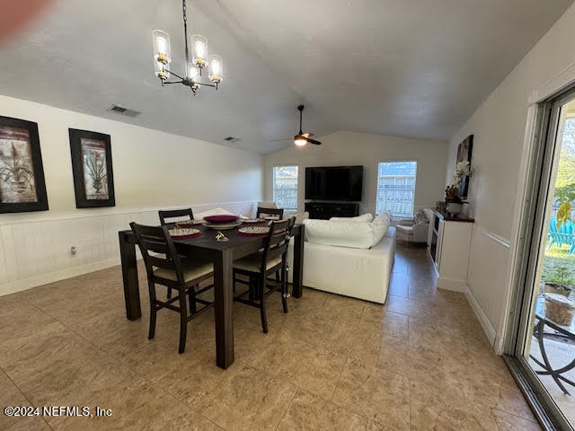 dining room featuring ceiling fan with notable chandelier and lofted ceiling