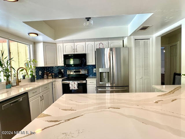 kitchen featuring light stone countertops, stainless steel appliances, tasteful backsplash, and sink