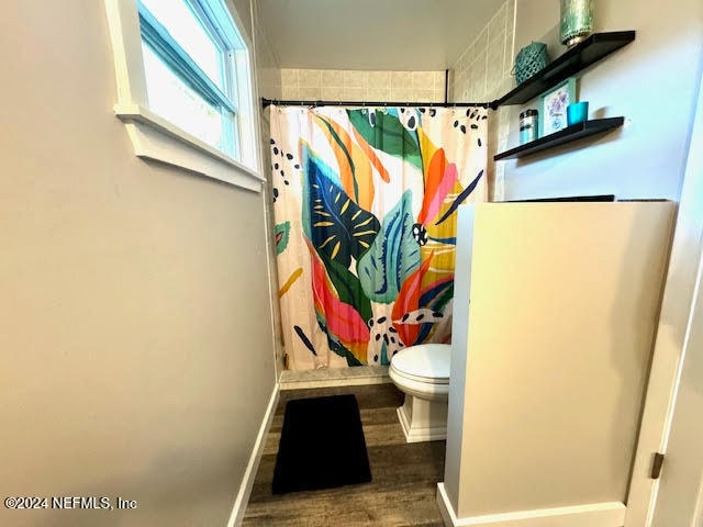 bathroom featuring hardwood / wood-style flooring, toilet, and walk in shower