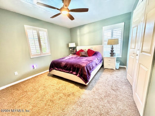 bedroom featuring multiple windows, ceiling fan, a closet, and carpet floors