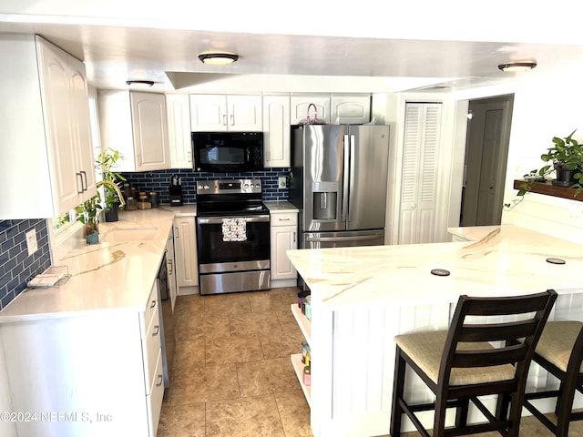 kitchen with a kitchen breakfast bar, white cabinetry, kitchen peninsula, and appliances with stainless steel finishes