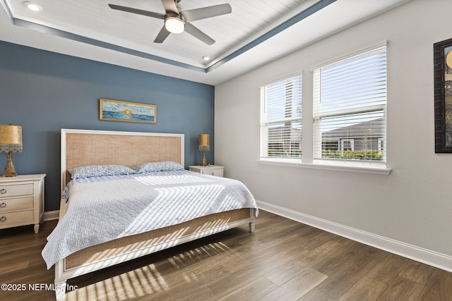 bedroom featuring recessed lighting, a raised ceiling, ceiling fan, wood finished floors, and baseboards