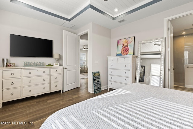 bedroom featuring a tray ceiling, dark wood-style flooring, recessed lighting, visible vents, and baseboards