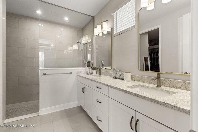 bathroom with a walk in shower, tile patterned flooring, a sink, a spacious closet, and double vanity