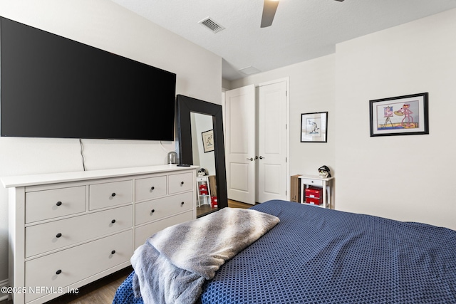 bedroom with wood finished floors, visible vents, and a ceiling fan