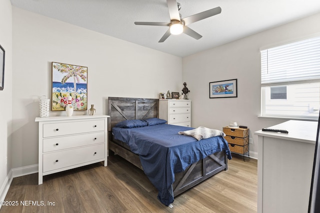 bedroom featuring a ceiling fan, baseboards, and wood finished floors