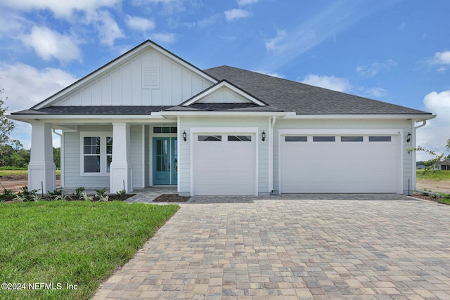 view of front of home featuring a front yard, a porch, and a garage