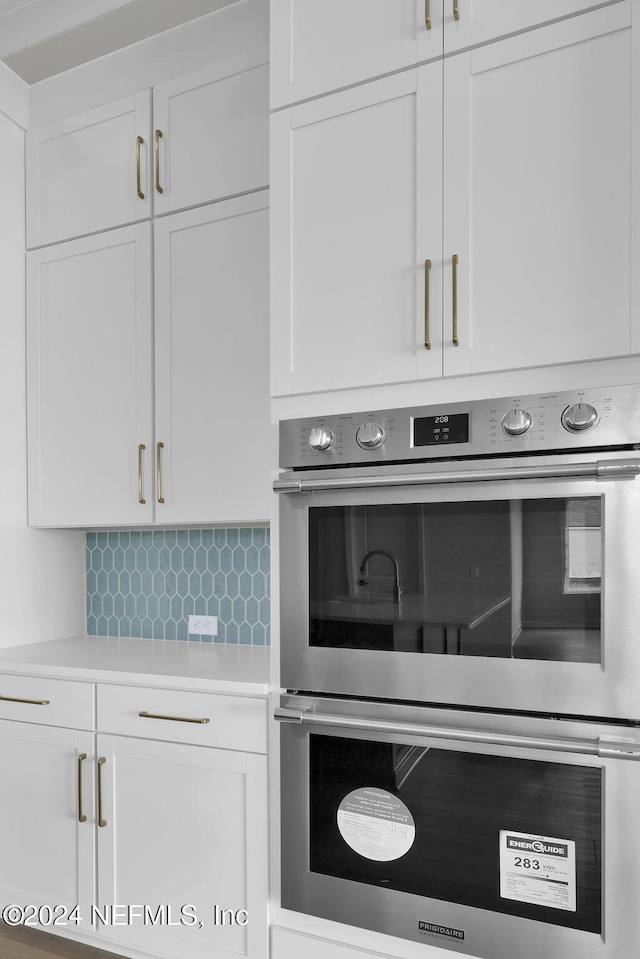 details featuring backsplash, white cabinetry, and double oven