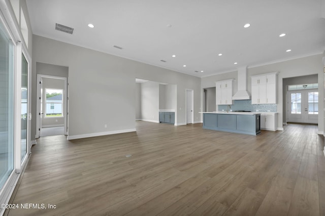 unfurnished living room with light wood-type flooring and crown molding