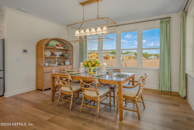 dining room featuring a chandelier, light wood-type flooring, and ornamental molding