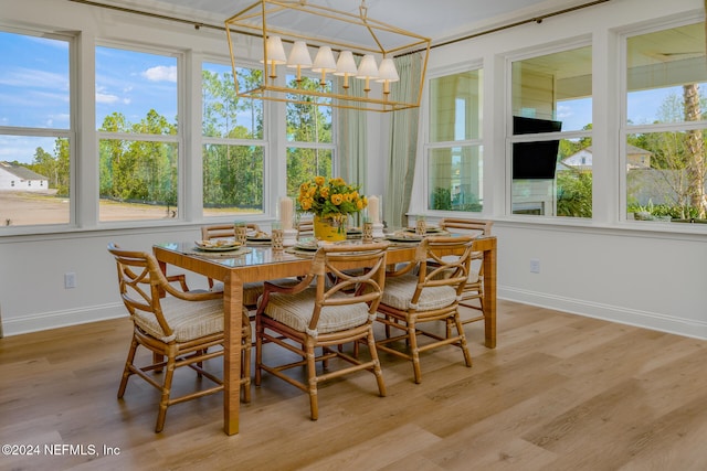 dining room with light wood-type flooring and an inviting chandelier