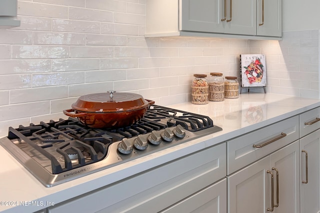 interior space with gray cabinets, backsplash, and stainless steel gas cooktop