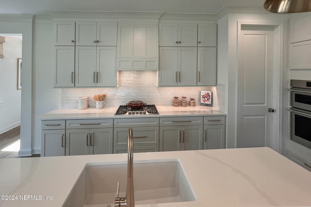 kitchen featuring tasteful backsplash, gray cabinetry, sink, and appliances with stainless steel finishes