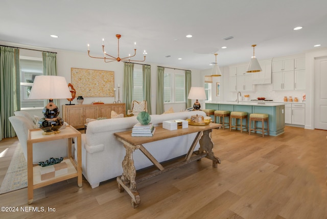 living room with a chandelier, sink, and light hardwood / wood-style floors