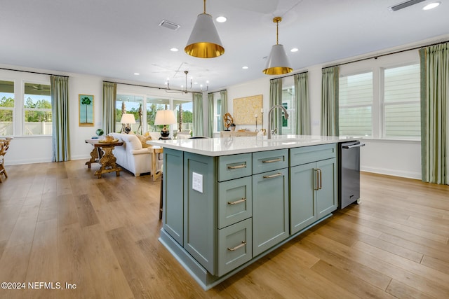 kitchen featuring a center island with sink, decorative light fixtures, light wood-type flooring, and sink