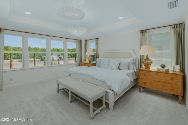 bedroom featuring a notable chandelier, a raised ceiling, and light colored carpet