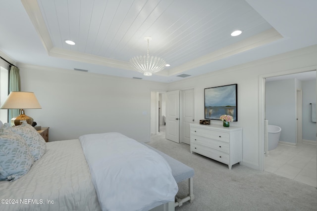 carpeted bedroom featuring ornamental molding, a tray ceiling, a notable chandelier, and ensuite bathroom