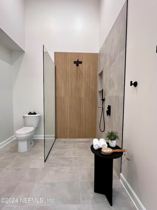 bathroom with tile patterned flooring, toilet, and a shower