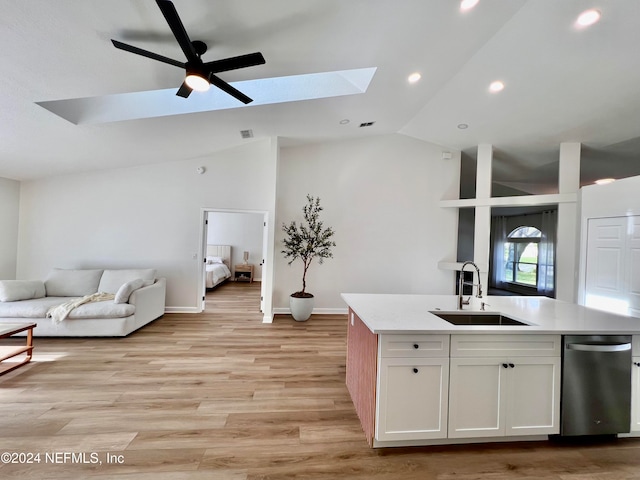 kitchen featuring light wood-type flooring, lofted ceiling with skylight, sink, white cabinets, and an island with sink