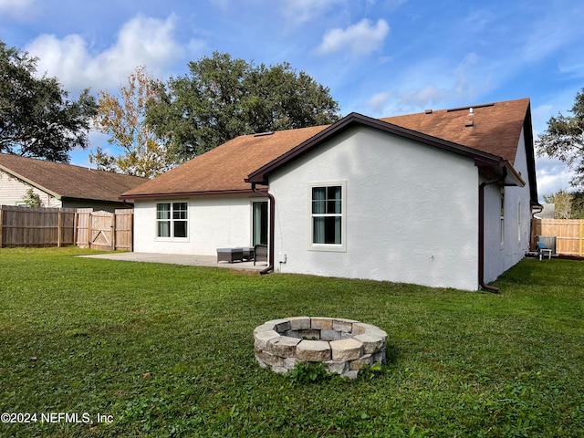 back of house with a yard, a patio, and a fire pit