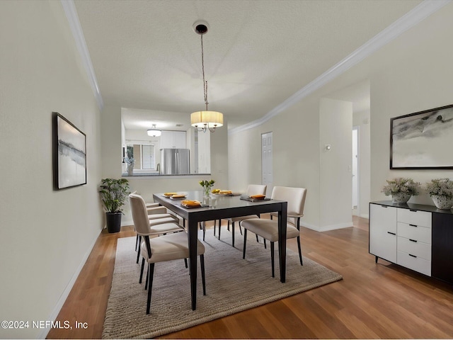 dining area with ornamental molding, hardwood / wood-style floors, and an inviting chandelier