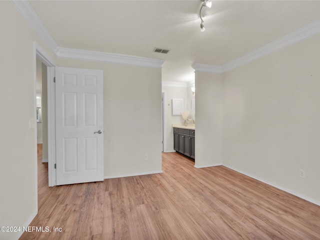 interior space featuring light hardwood / wood-style flooring, ornamental molding, and ensuite bathroom