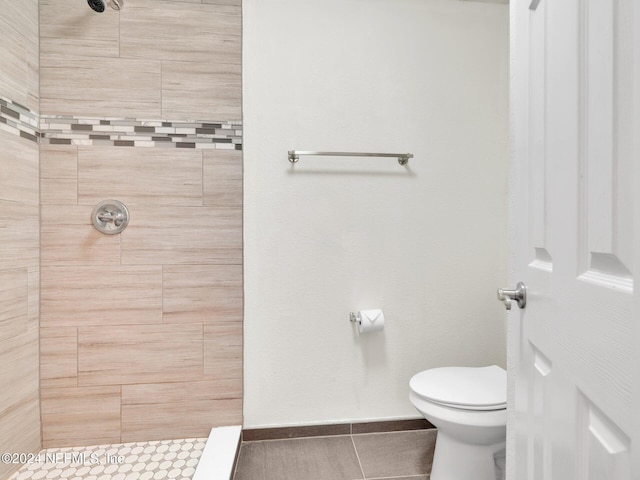 bathroom with a tile shower, tile patterned flooring, and toilet