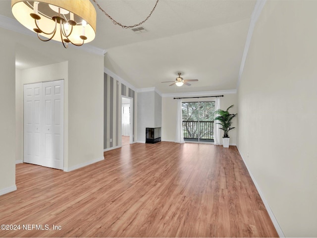 unfurnished living room featuring crown molding, ceiling fan with notable chandelier, wood-type flooring, and a wood stove