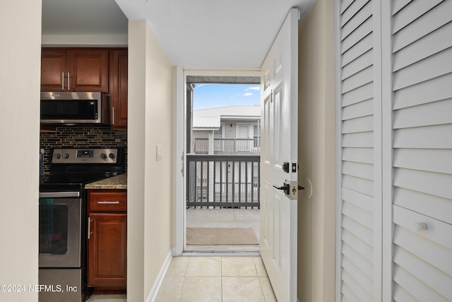 interior space with light tile patterned floors, backsplash, stainless steel appliances, and stone countertops