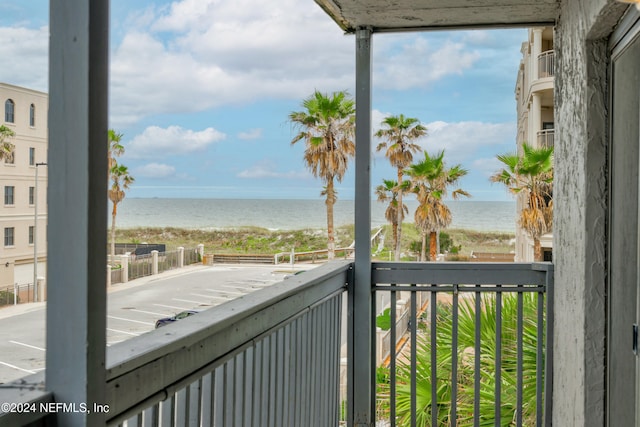 balcony with a water view and a view of the beach