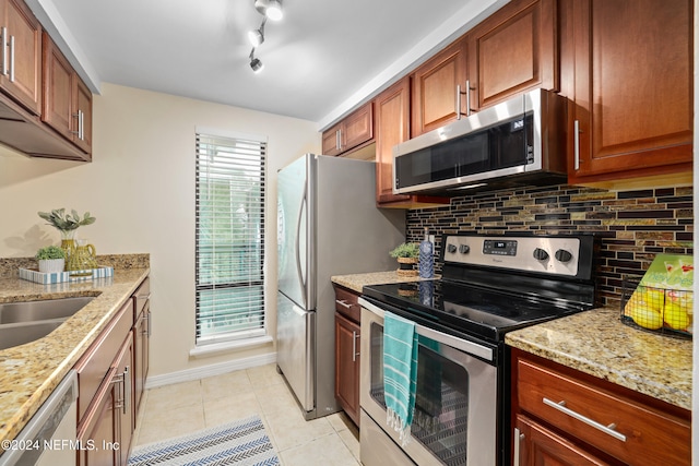 kitchen featuring decorative backsplash, stainless steel appliances, light stone countertops, and light tile patterned flooring