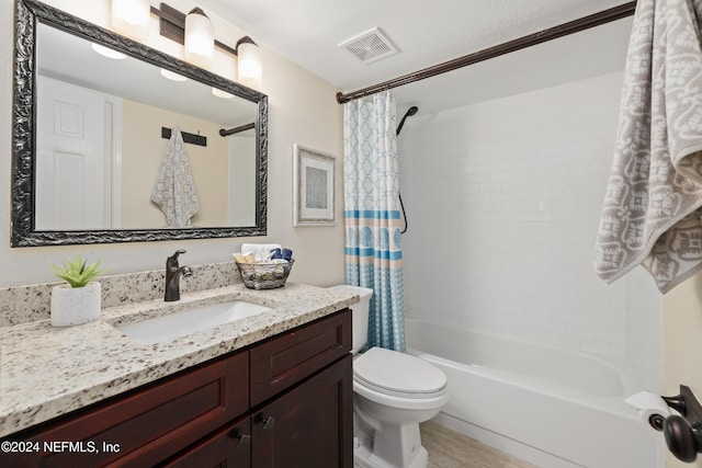 full bathroom featuring vanity, toilet, shower / bath combo with shower curtain, and a textured ceiling