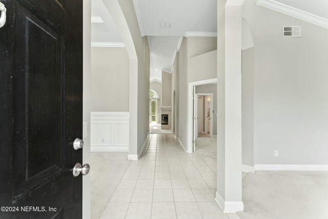 carpeted foyer featuring lofted ceiling and ornamental molding