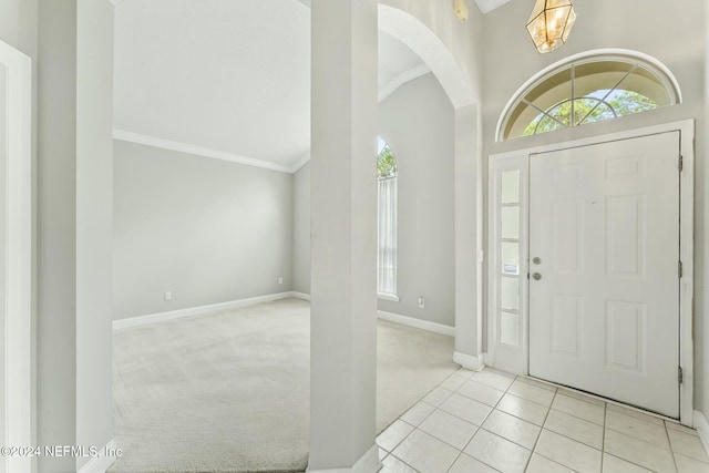 carpeted entryway featuring a high ceiling and ornamental molding